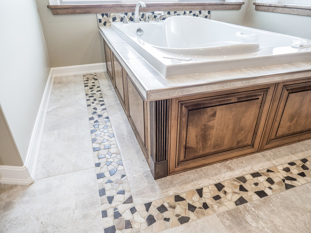 Photo of a large classic ensuite bathroom in Edmonton with raised-panel cabinets, brown cabinets, a hot tub, a corner shower, a two-piece toilet, multi-coloured tiles, marble tiles, beige walls, marble flooring, a built-in sink, granite worktops, multi-coloured floors and a hinged door.