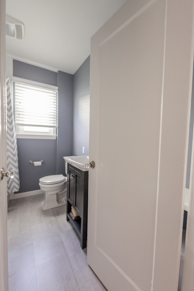 Inredning av ett modernt litet badrum, med ett nedsänkt handfat, luckor med infälld panel, grå skåp, bänkskiva i akrylsten, ett badkar i en alkov, en dusch i en alkov, en toalettstol med hel cisternkåpa, vit kakel, porslinskakel, grå väggar och klinkergolv i porslin