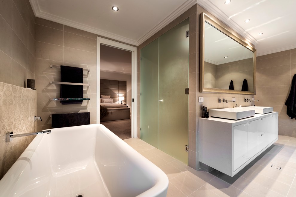 Large contemporary ensuite bathroom in Perth with recessed-panel cabinets, white cabinets, a freestanding bath, a double shower, a one-piece toilet, beige tiles, porcelain tiles, beige walls, porcelain flooring, a vessel sink, engineered stone worktops, beige floors, a hinged door and beige worktops.