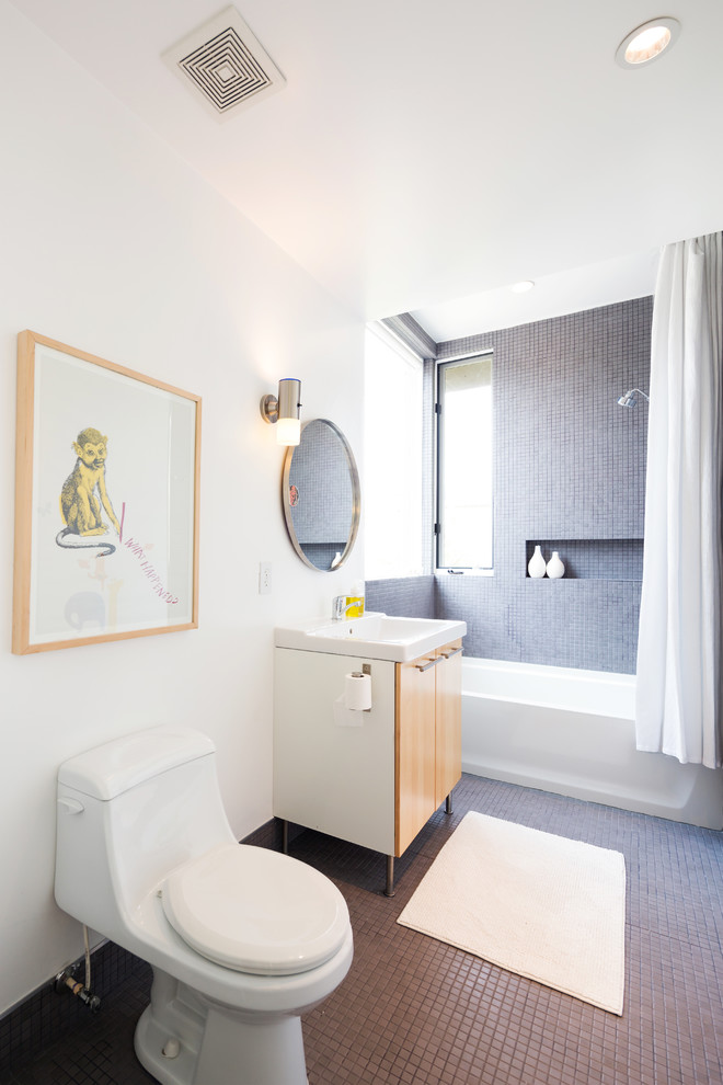 На фото: ванная комната в современном стиле с плоскими фасадами, фасадами цвета дерева среднего тона, ванной в нише, душем над ванной, унитазом-моноблоком, серой плиткой, белыми стенами и окном