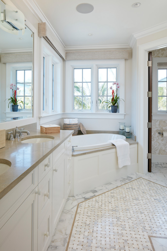 Large beach style master marble floor and white floor drop-in bathtub photo in Denver with recessed-panel cabinets, white cabinets, beige walls, an undermount sink, soapstone countertops and a one-piece toilet
