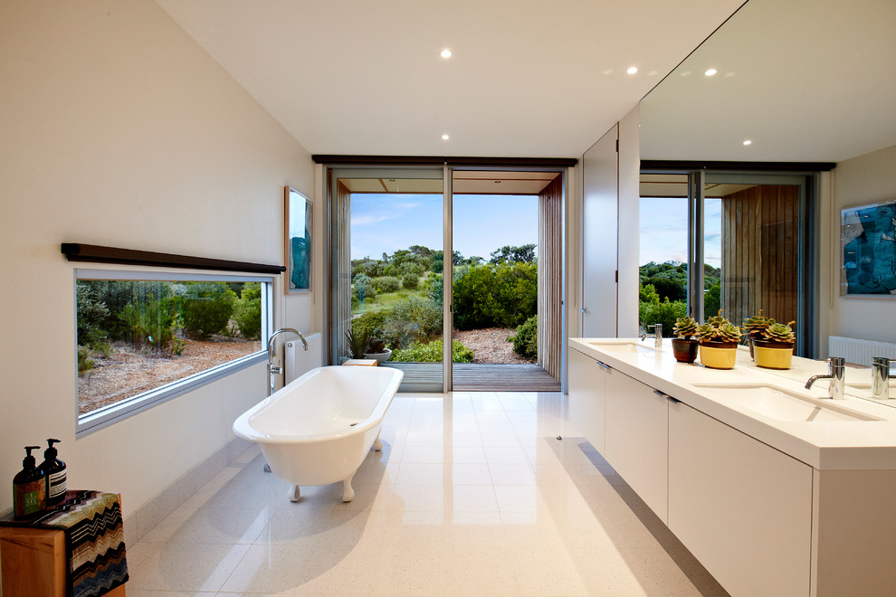 Idée de décoration pour une salle de bain design avec un lavabo encastré, un placard à porte plane, des portes de placard blanches, une baignoire indépendante et un mur blanc.