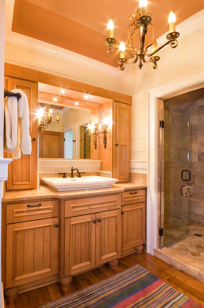 Bathroom - traditional master beige tile and stone tile medium tone wood floor bathroom idea in Charleston with a vessel sink, recessed-panel cabinets, medium tone wood cabinets, limestone countertops and white walls
