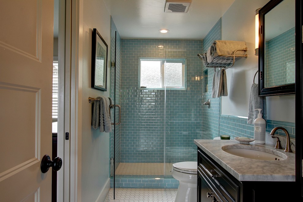 Exemple d'une douche en alcôve principale bord de mer avec un placard à porte shaker, des portes de placard noires, un carrelage bleu, un carrelage métro, un mur blanc, un lavabo encastré, un plan de toilette en marbre, un sol blanc et une cabine de douche à porte battante.
