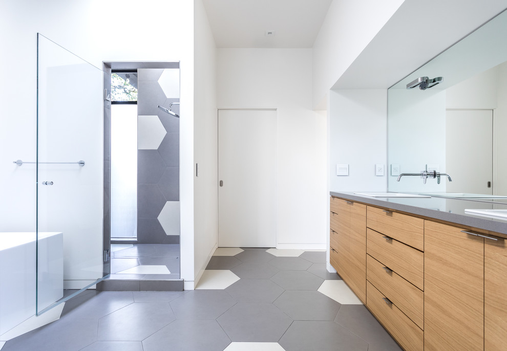 Пример оригинального дизайна: главная ванная комната в стиле модернизм с плоскими фасадами, светлыми деревянными фасадами, отдельно стоящей ванной, душем в нише, серой плиткой, белой плиткой, белыми стенами, накладной раковиной, серым полом, душем с распашными дверями и серой столешницей