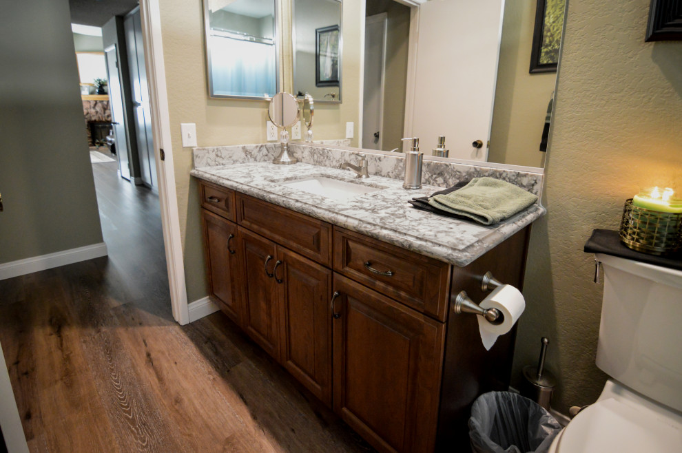This is an example of a small classic family bathroom in Los Angeles with raised-panel cabinets, dark wood cabinets, a two-piece toilet, beige walls, dark hardwood flooring, a submerged sink, engineered stone worktops and multi-coloured worktops.