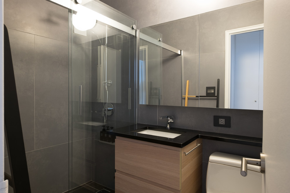 Mid-sized trendy 3/4 gray tile and slate tile bathroom photo in New York with flat-panel cabinets, light wood cabinets, a two-piece toilet, gray walls, an undermount sink and quartz countertops