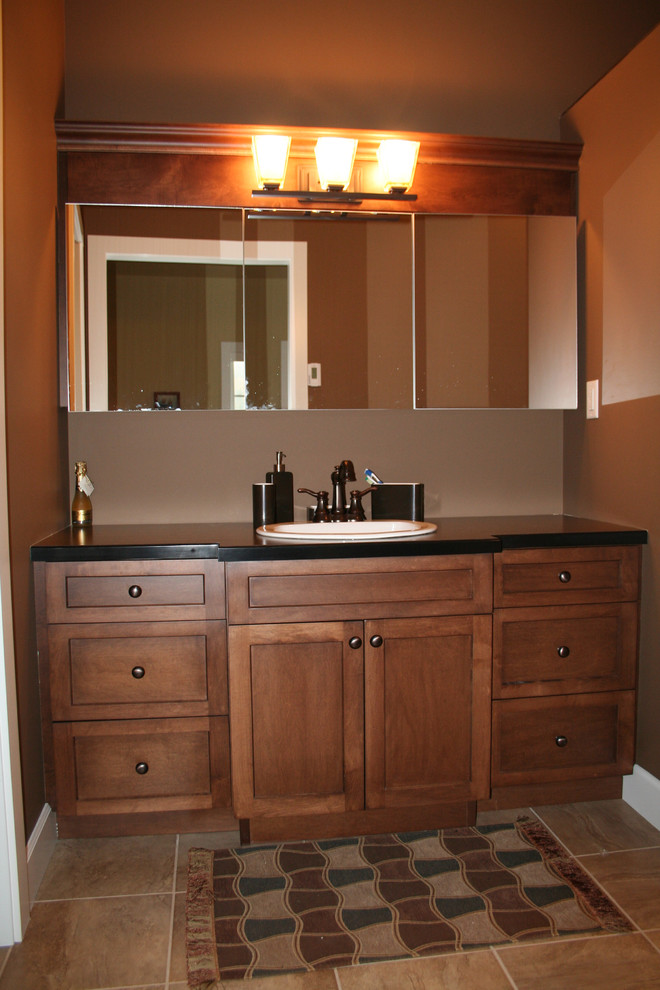 バンクーバーにある小さなトラディショナルスタイルのおしゃれな浴室 (オーバーカウンターシンク、シェーカースタイル扉のキャビネット、中間色木目調キャビネット、ラミネートカウンター、茶色い壁) の写真