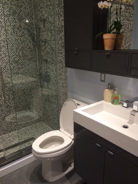 Idée de décoration pour une petite salle de bain minimaliste avec un lavabo posé, un placard à porte plane, des portes de placard grises, un plan de toilette en calcaire, une douche ouverte, WC à poser, un carrelage gris, des carreaux de porcelaine, un mur gris et un sol en carrelage de porcelaine.