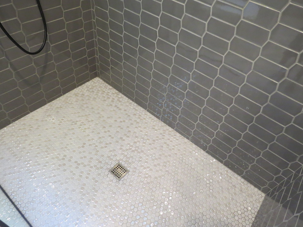 Bild på ett mellanstort industriellt en-suite badrum, med släta luckor, grå skåp, en dusch i en alkov, en toalettstol med separat cisternkåpa, grå kakel, keramikplattor, grå väggar, klinkergolv i porslin, ett undermonterad handfat, bänkskiva i kvarts, grått golv och med dusch som är öppen