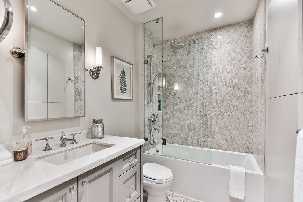 Пример оригинального дизайна: ванная комната в классическом стиле с фасадами с утопленной филенкой, серыми фасадами, ванной в нише, серой плиткой, плиткой мозаикой, серыми стенами, полом из мозаичной плитки, душевой кабиной, врезной раковиной, разноцветным полом, белой столешницей и нишей