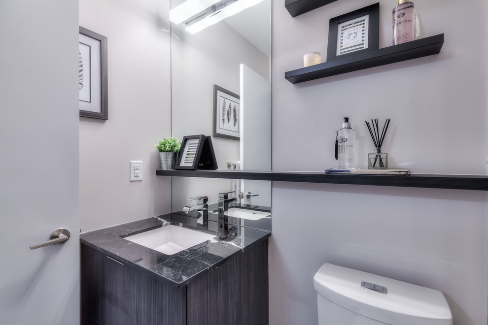 Cette image montre une petite salle de bain design en bois foncé avec un placard à porte plane, un carrelage gris, des carreaux de céramique, un mur gris, un sol en carrelage de céramique et un plan de toilette en granite.