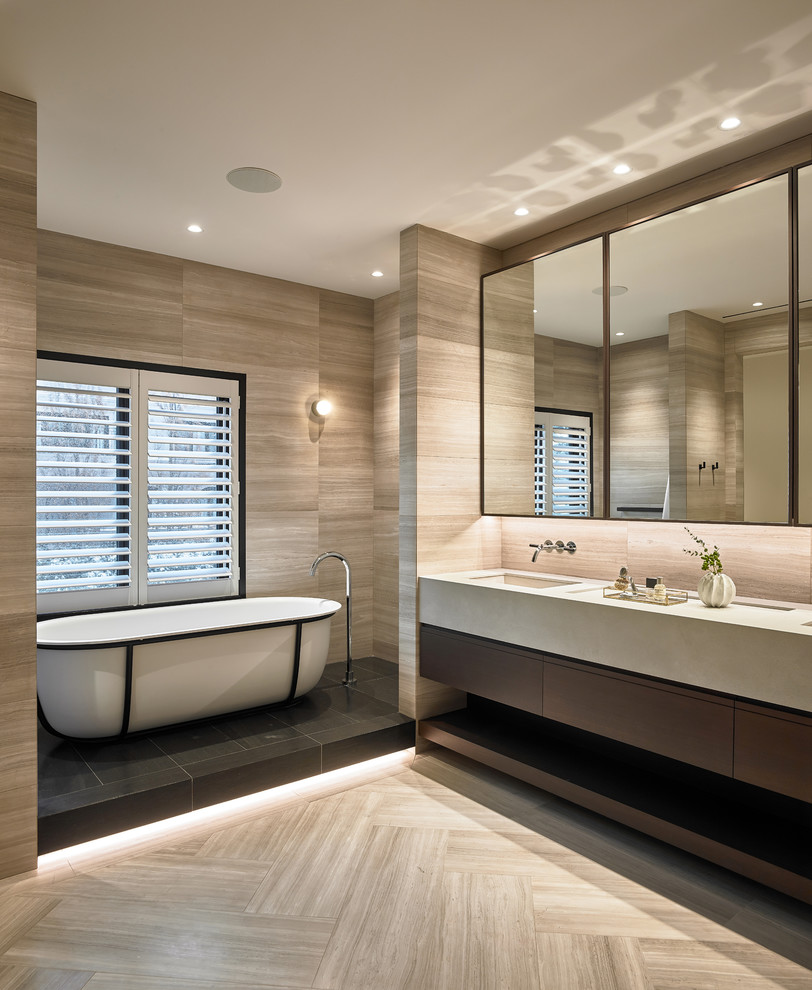 Идея дизайна: главная ванная комната в современном стиле с плоскими фасадами, темными деревянными фасадами, отдельно стоящей ванной, бежевой плиткой, бежевыми стенами, врезной раковиной, бежевым полом, бежевой столешницей и зеркалом с подсветкой