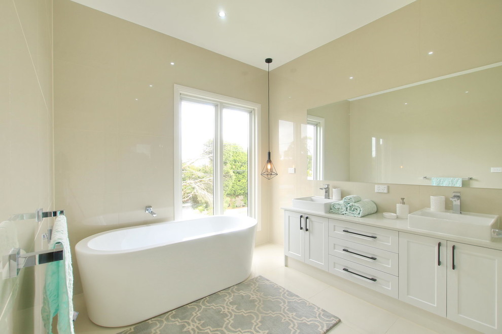 This is an example of a medium sized classic shower room bathroom with white cabinets, a freestanding bath, a double shower, a one-piece toilet, beige tiles, ceramic tiles, beige walls, ceramic flooring, a pedestal sink, granite worktops, beige floors and a hinged door.
