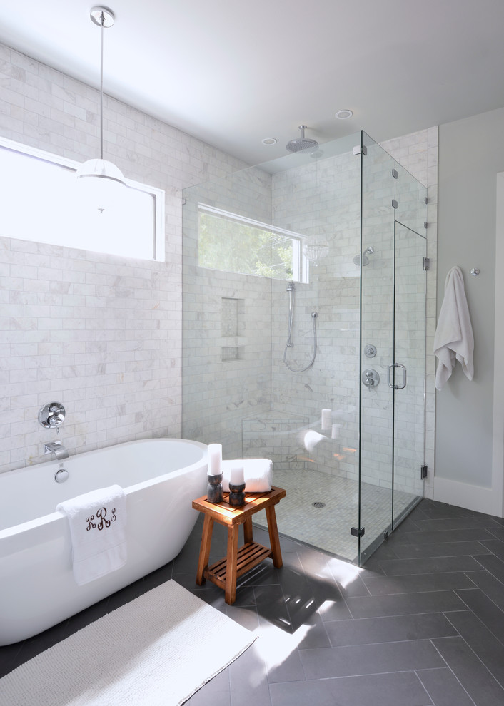 Cette image montre une salle de bain traditionnelle avec une baignoire indépendante, une douche d'angle, un carrelage blanc, un mur gris et un sol gris.