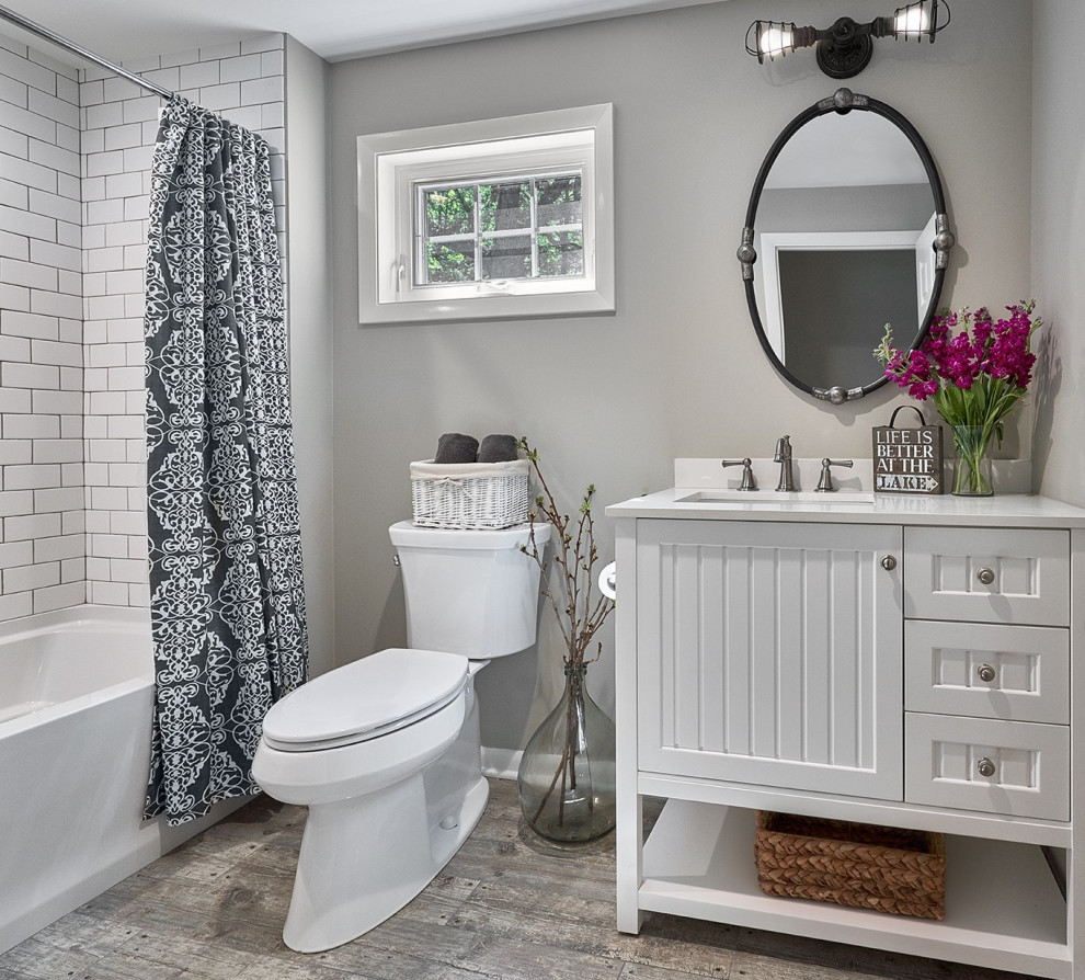 Idée de décoration pour une petite salle d'eau champêtre avec un placard en trompe-l'oeil, des portes de placard blanches, une baignoire en alcôve, un combiné douche/baignoire, WC séparés, un carrelage blanc, des carreaux de céramique, un mur gris, un sol en carrelage de porcelaine, un plan de toilette en quartz modifié, un sol gris, un plan de toilette blanc, meuble simple vasque et meuble-lavabo encastré.