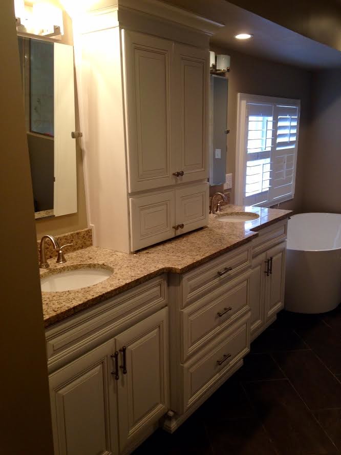 Medium sized traditional ensuite bathroom in Orange County with raised-panel cabinets, white cabinets, a freestanding bath, brown walls, porcelain flooring, granite worktops, a submerged sink and brown floors.