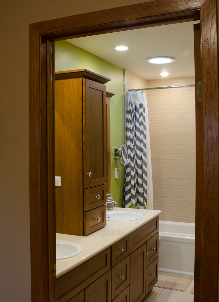 Bild på ett mellanstort funkis en-suite badrum, med ett nedsänkt handfat, luckor med infälld panel, skåp i mörkt trä, laminatbänkskiva, ett platsbyggt badkar, en dusch/badkar-kombination, en toalettstol med separat cisternkåpa, beige kakel, keramikplattor, gröna väggar och klinkergolv i porslin