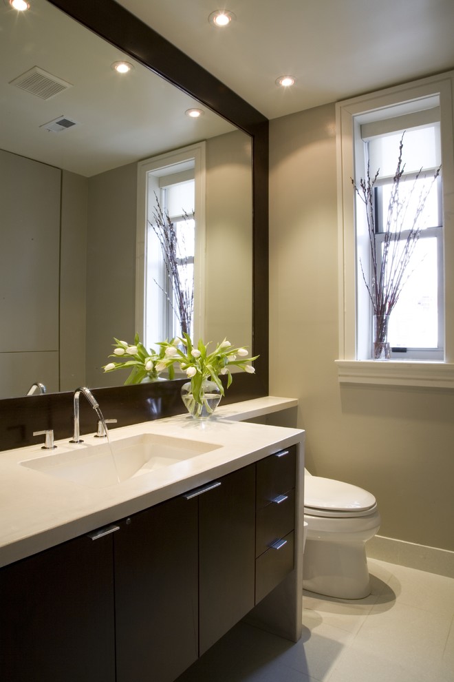 Aménagement d'une salle de bain contemporaine en bois foncé avec un lavabo encastré, un placard à porte plane et un plan de toilette beige.