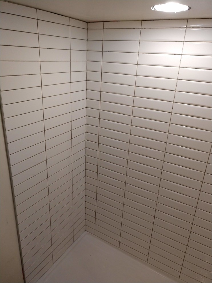 Großes Modernes Badezimmer En Suite mit flächenbündigen Schrankfronten, bodengleicher Dusche, Toilette mit Aufsatzspülkasten, weißen Fliesen, Keramikfliesen, weißer Wandfarbe, Porzellan-Bodenfliesen, integriertem Waschbecken, grauem Boden und offener Dusche in Grand Rapids