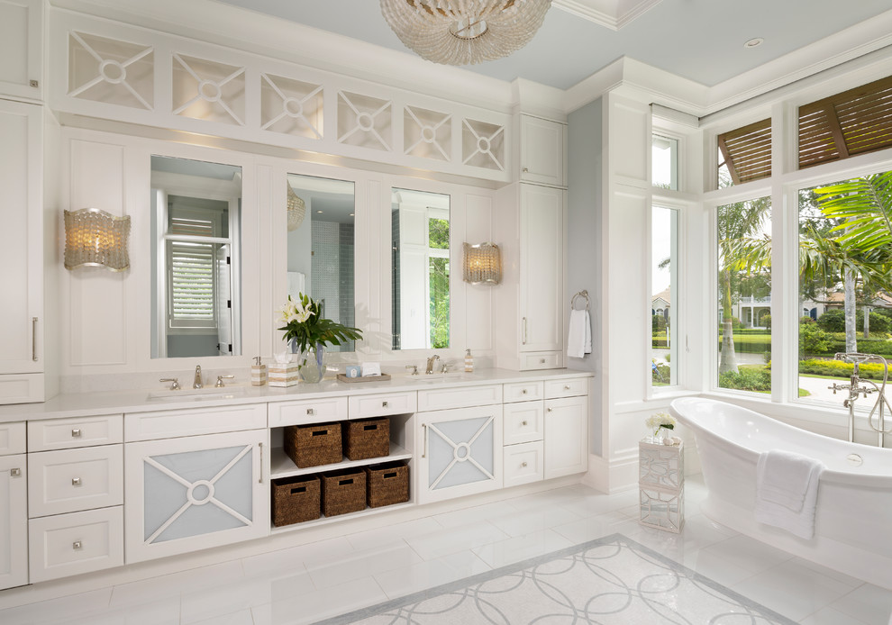 Immagine di una stanza da bagno stile marino con ante con riquadro incassato, ante bianche, vasca freestanding, pareti grigie, lavabo sottopiano, pavimento bianco e top bianco
