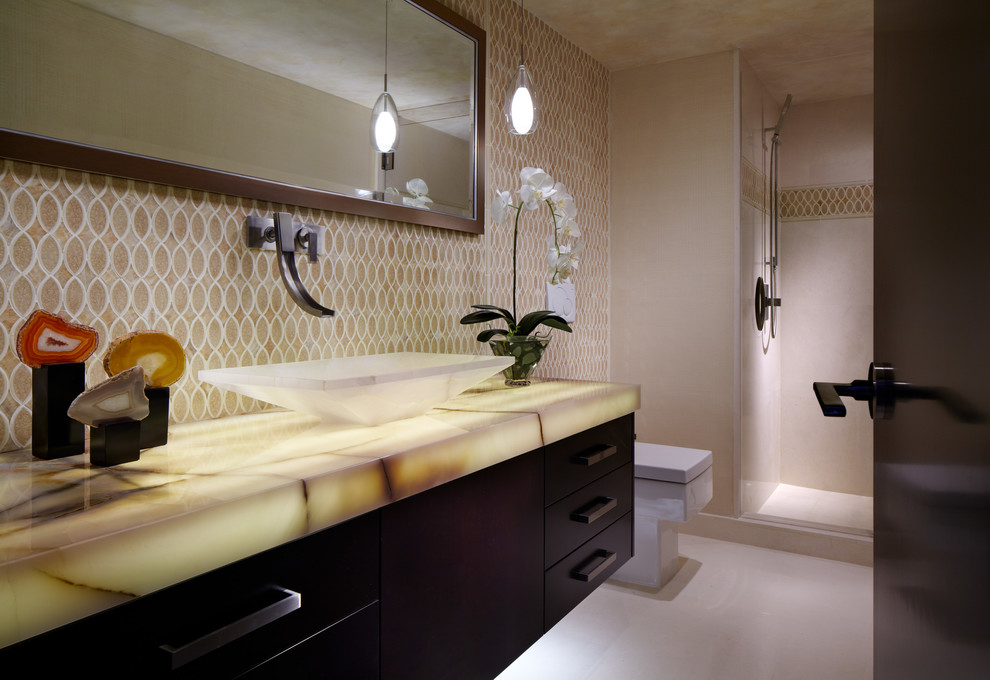 Design ideas for a medium sized contemporary shower room bathroom in Miami with a submerged sink, flat-panel cabinets, dark wood cabinets, limestone worktops, a walk-in shower, a one-piece toilet, beige tiles, glass tiles, beige walls and limestone flooring.