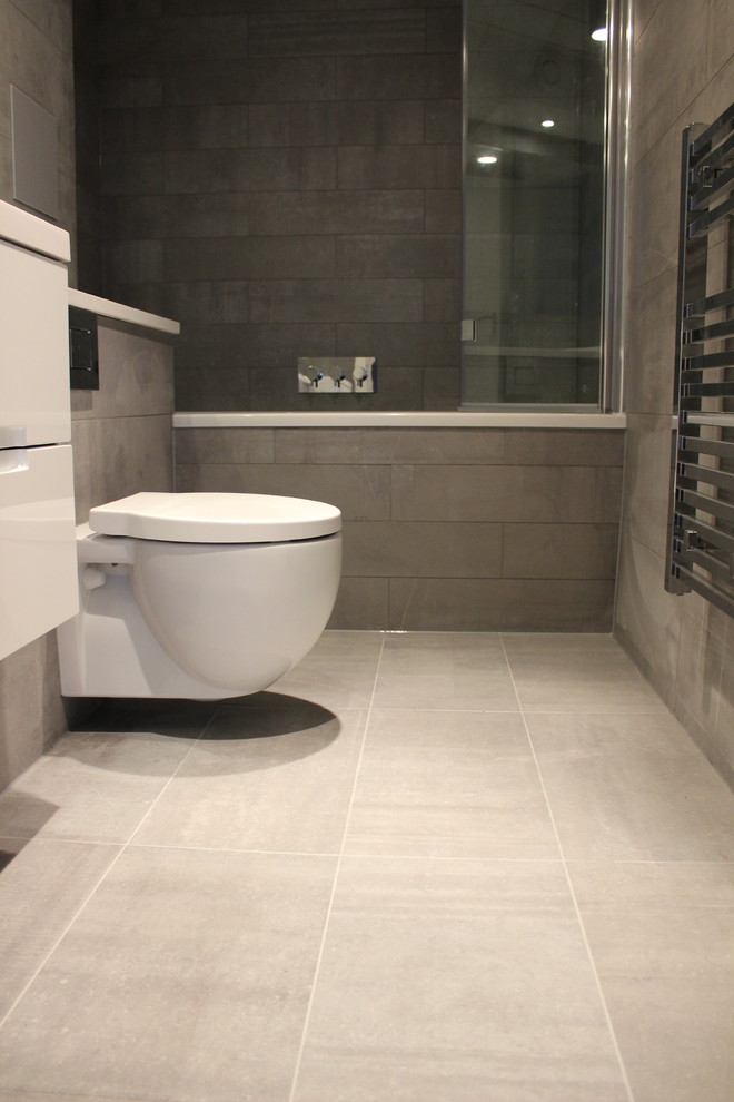 Mid-sized minimalist gray tile and stone tile bathroom photo in London with a wall-mount toilet and gray walls