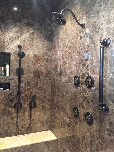 На фото: большая главная ванная комната в классическом стиле с фасадами островного типа, темными деревянными фасадами, гидромассажной ванной, двойным душем, унитазом-моноблоком, коричневой плиткой, мраморной плиткой, бежевыми стенами, полом из керамогранита, врезной раковиной, мраморной столешницей, бежевым полом и душем с распашными дверями
