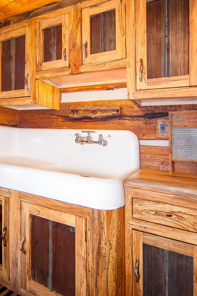Modelo de cuarto de baño rústico de tamaño medio con armarios tipo mueble, puertas de armario con efecto envejecido, paredes marrones, suelo de madera en tonos medios, aseo y ducha, lavabo de seno grande y encimera de madera