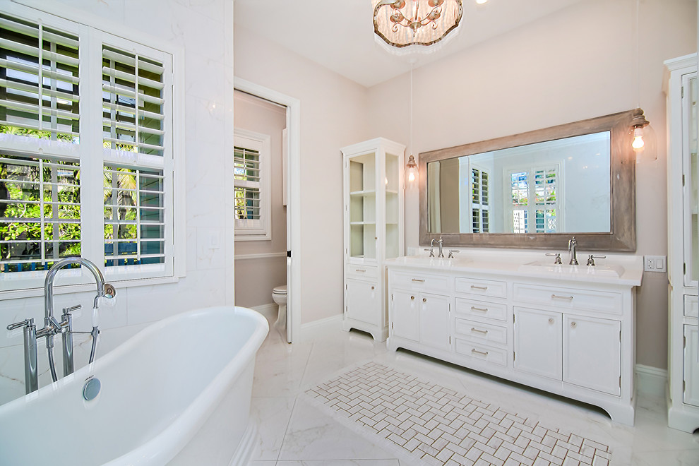 Aménagement d'une salle de bain principale classique de taille moyenne avec un placard à porte affleurante, une baignoire indépendante, une douche d'angle, WC séparés, un carrelage blanc, des carreaux de porcelaine, un mur gris, un sol en carrelage de porcelaine, un lavabo posé, un plan de toilette en quartz modifié, un sol blanc, aucune cabine et des portes de placard blanches.