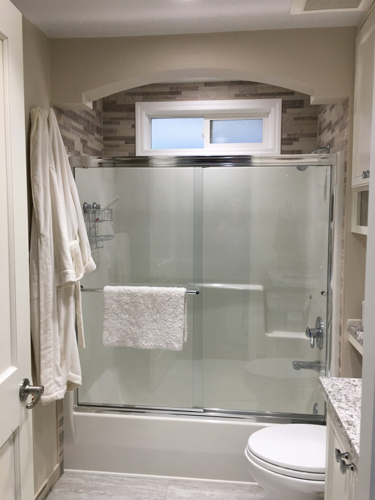 Exempel på ett mellanstort klassiskt grå grått badrum, med luckor med upphöjd panel, vita skåp, ett badkar i en alkov, en dusch/badkar-kombination, en toalettstol med separat cisternkåpa, beige kakel, stenkakel, beige väggar, linoleumgolv, ett undermonterad handfat, granitbänkskiva, grått golv och dusch med skjutdörr
