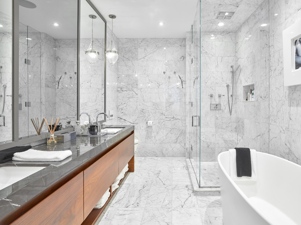 Пример оригинального дизайна: главная ванная комната в современном стиле с плоскими фасадами, темными деревянными фасадами, отдельно стоящей ванной, угловым душем, белой плиткой, врезной раковиной, белым полом, душем с распашными дверями и серой столешницей