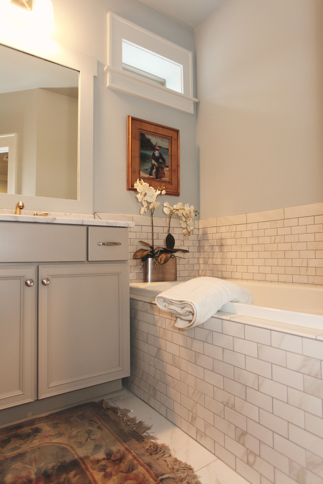 Idée de décoration pour une salle de bain craftsman avec des portes de placard grises, un plan de toilette en granite, une baignoire posée, un carrelage blanc, des carreaux de porcelaine, un mur bleu et un sol en carrelage de porcelaine.