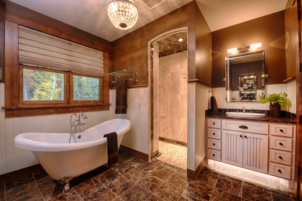 На фото: главная ванная комната в стиле рустика с белыми фасадами, ванной на ножках, коричневыми стенами, накладной раковиной и окном