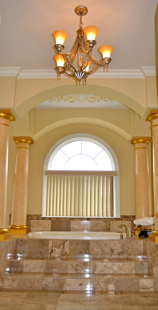Ejemplo de cuarto de baño principal tradicional grande con bañera encastrada, baldosas y/o azulejos beige, baldosas y/o azulejos de piedra, paredes amarillas y suelo de travertino