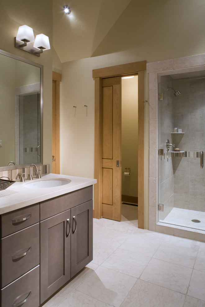 This is an example of a contemporary bathroom in Denver with a submerged sink, shaker cabinets, brown cabinets, beige tiles and feature lighting.