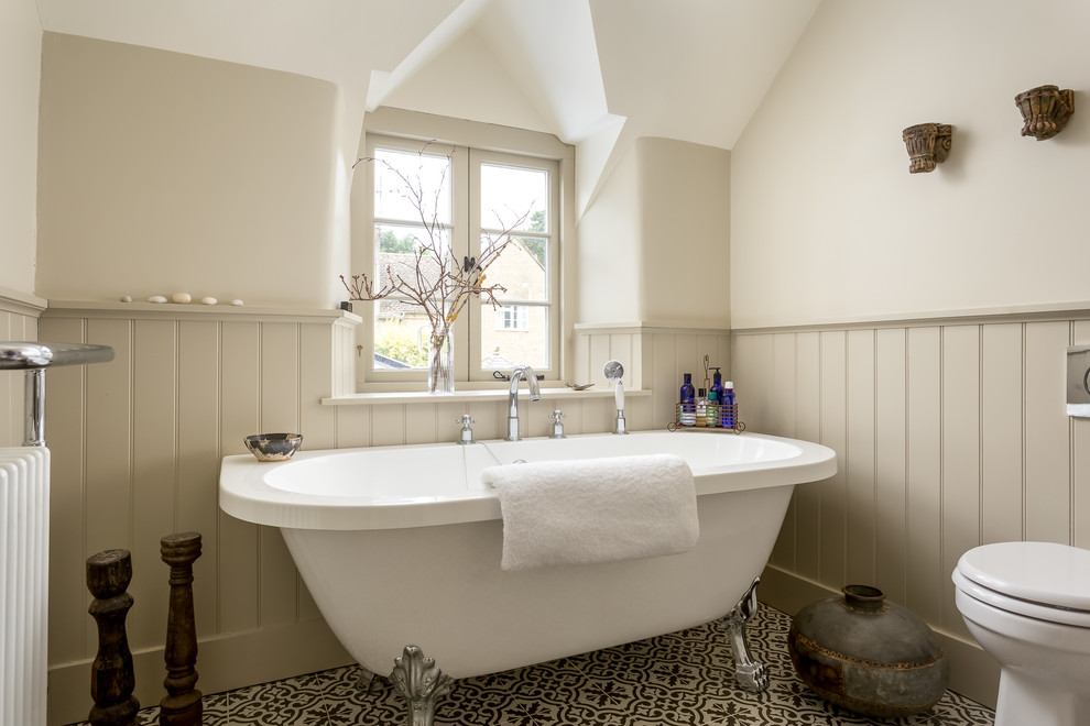 Example of a mid-sized cottage master freestanding bathtub design in Gloucestershire with a one-piece toilet and beige walls