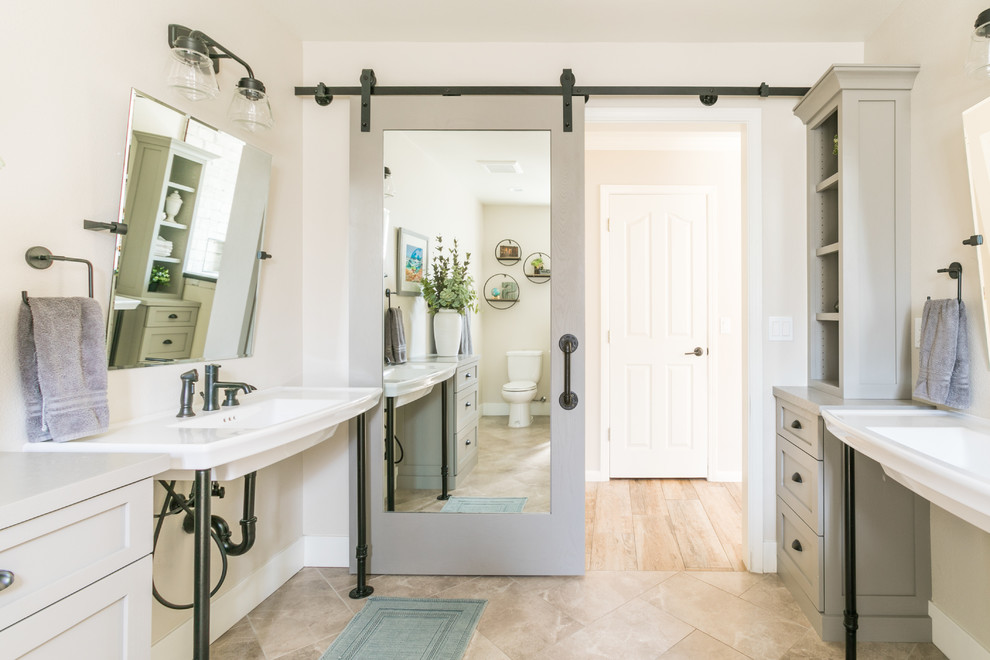 Design ideas for a country bathroom in Santa Barbara with recessed-panel cabinets, grey cabinets, beige walls, a console sink and beige floors.