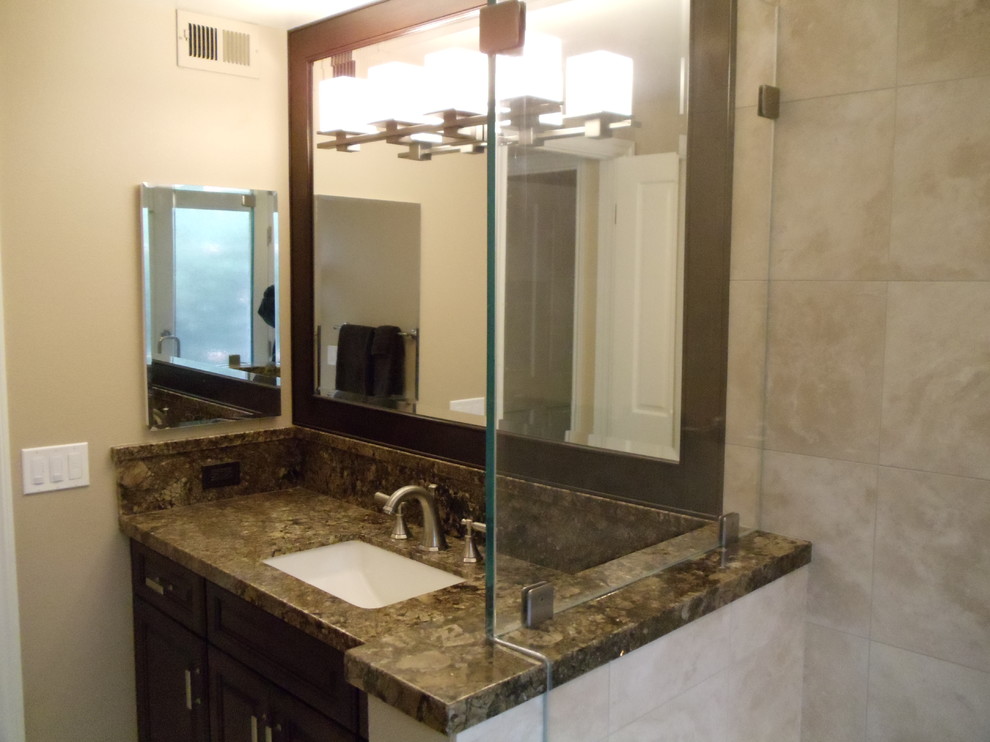 Medium sized contemporary ensuite bathroom in Los Angeles with a submerged sink, flat-panel cabinets, dark wood cabinets, granite worktops, an alcove bath, a shower/bath combination, a two-piece toilet, beige tiles, stone tiles, beige walls and travertine flooring.