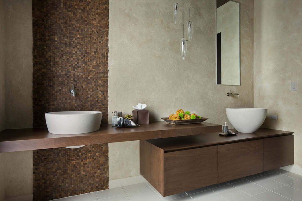Modern inredning av ett stort brun brunt en-suite badrum, med ett fristående handfat, brun kakel, släta luckor, skåp i mörkt trä, träbänkskiva, mosaik, beige väggar och klinkergolv i keramik