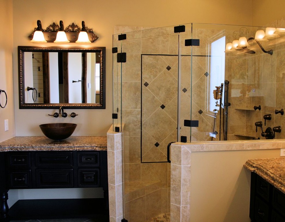 Klassisk inredning av ett badrum, med skåp i mörkt trä, granitbänkskiva, en hörndusch, beige kakel, beige väggar och ett fristående handfat