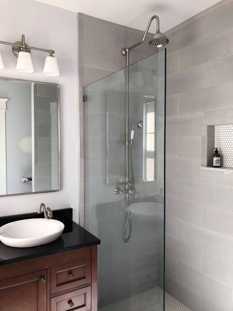 Photo of a medium sized traditional shower room bathroom in Baltimore with recessed-panel cabinets, dark wood cabinets, a built-in shower, a two-piece toilet, grey tiles, ceramic tiles, blue walls, ceramic flooring, a vessel sink, granite worktops, grey floors, an open shower and black worktops.