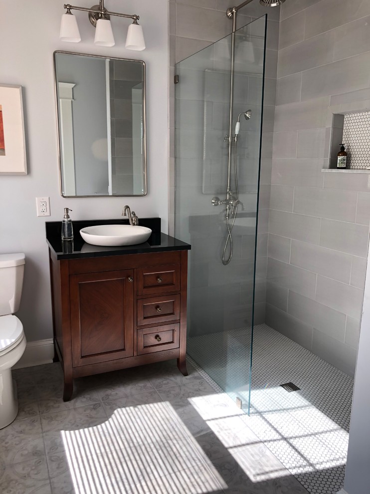 Photo of a medium sized classic shower room bathroom in Baltimore with recessed-panel cabinets, dark wood cabinets, a built-in shower, a two-piece toilet, grey tiles, ceramic tiles, blue walls, ceramic flooring, a vessel sink, granite worktops, grey floors, an open shower and black worktops.