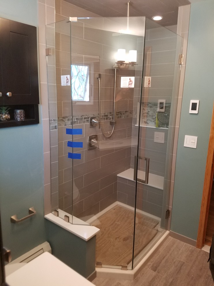 Example of a mid-sized trendy master gray tile and ceramic tile travertine floor and white floor corner shower design in Newark with a one-piece toilet, yellow walls, a pedestal sink, a hinged shower door and beige countertops