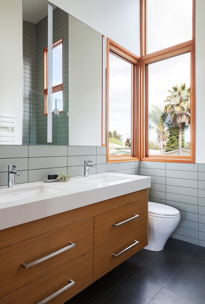 Modernes Badezimmer mit flächenbündigen Schrankfronten, hellbraunen Holzschränken, weißen Fliesen, weißer Wandfarbe, Unterbauwaschbecken, schwarzem Boden und weißer Waschtischplatte in San Francisco