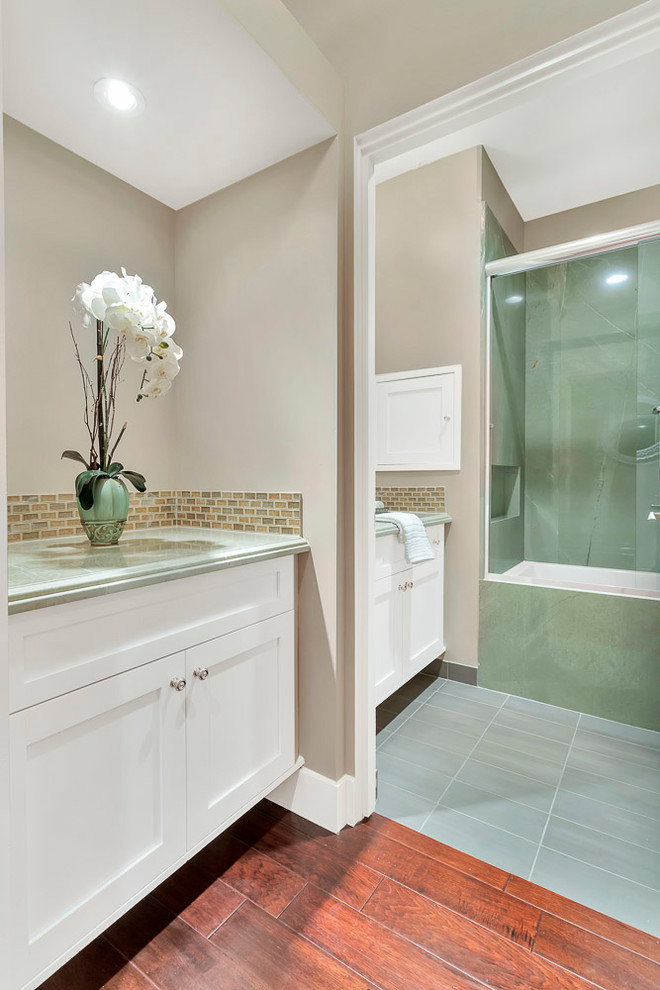Идея дизайна: ванная комната среднего размера в стиле ретро с фасадами с выступающей филенкой, белыми фасадами, ванной в нише, угловым душем, раздельным унитазом, разноцветной плиткой, каменной плиткой, розовыми стенами, полом из цементной плитки, душевой кабиной, врезной раковиной, столешницей из гранита, зеленым полом, душем с раздвижными дверями и зеленой столешницей