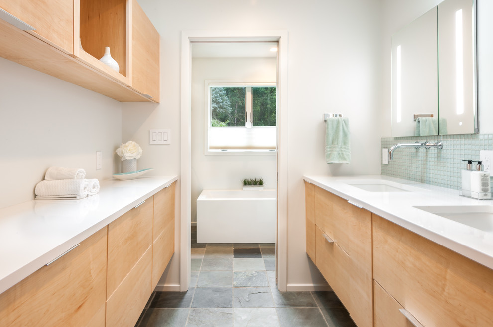 Immagine di una stanza da bagno moderna di medie dimensioni con ante lisce, ante in legno chiaro, vasca freestanding, piastrelle blu, piastrelle di vetro, pareti bianche, pavimento in ardesia, lavabo sottopiano, pavimento grigio e porta doccia scorrevole