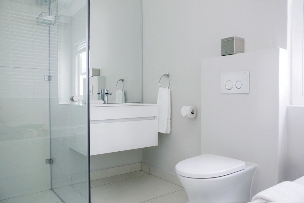Design ideas for a small contemporary family bathroom in Other with flat-panel cabinets, white cabinets, a built-in bath, a corner shower, a wall mounted toilet, beige tiles, porcelain tiles, white walls, porcelain flooring, a submerged sink and engineered stone worktops.
