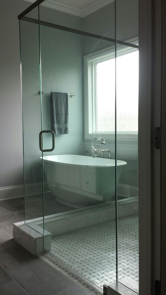 Immagine di una stanza da bagno padronale minimal di medie dimensioni con vasca freestanding, doccia a filo pavimento, piastrelle beige, piastrelle in pietra, pareti grigie, pavimento grigio e porta doccia a battente