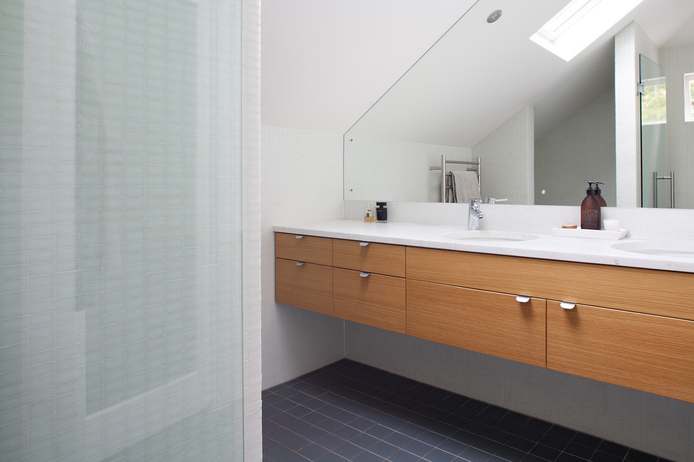 This is an example of a modern bathroom in Auckland with light wood cabinets, porcelain flooring and marble worktops.